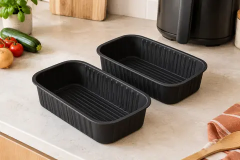 Deux moules rectangulaires en silicone noir posés sur un plan de travail clair, avec leurs rainures visibles.