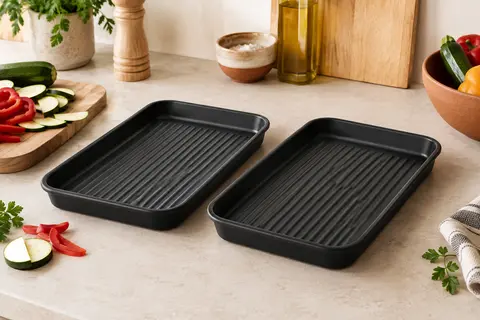 Deux moules en silicone noir à fond rainuré posés sur un plan de travail clair de cuisine